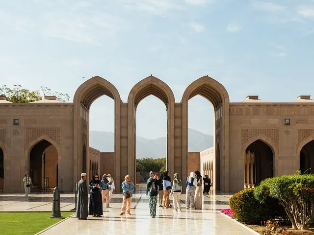 Toeristen die de grote bogen van de Sultan Qaboos Grand Mosque in Muscat verkennen.