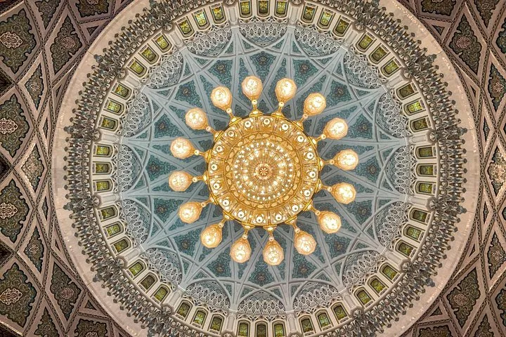Sierlijk plafond en de indrukwekkende kroonluchter in de Sultan Qaboos Grand Mosque.