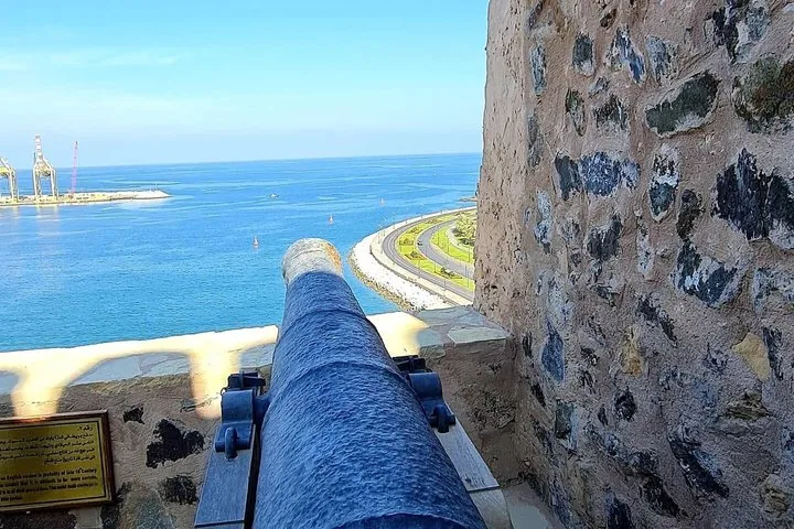 An old cannon pointing towards the harbor from a historic fort in Muscat.